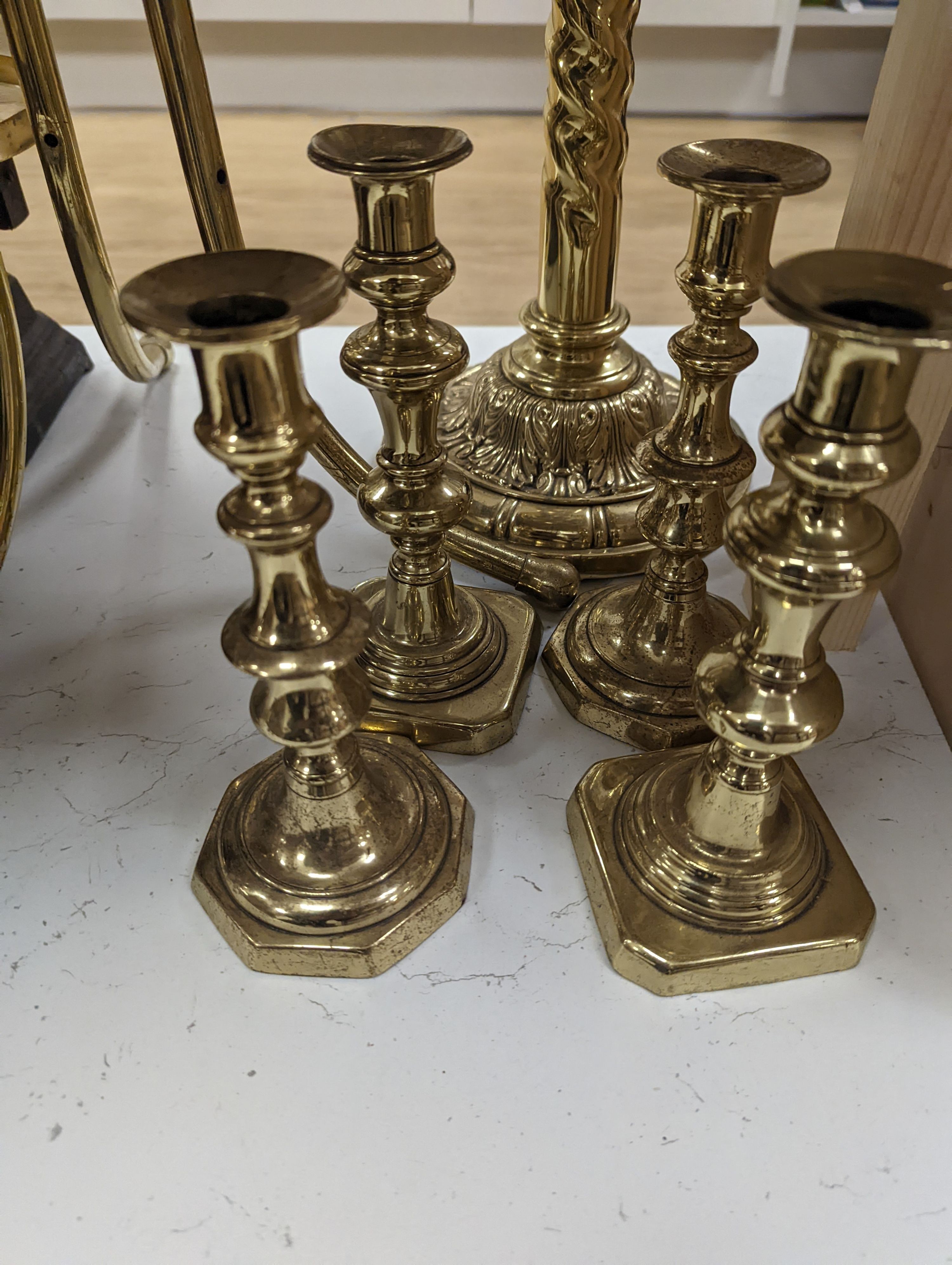 A brass magazine stand, a pair of scales, four candlesticks and a tall brass oil lamp base, Oil lamp 58 cms high.